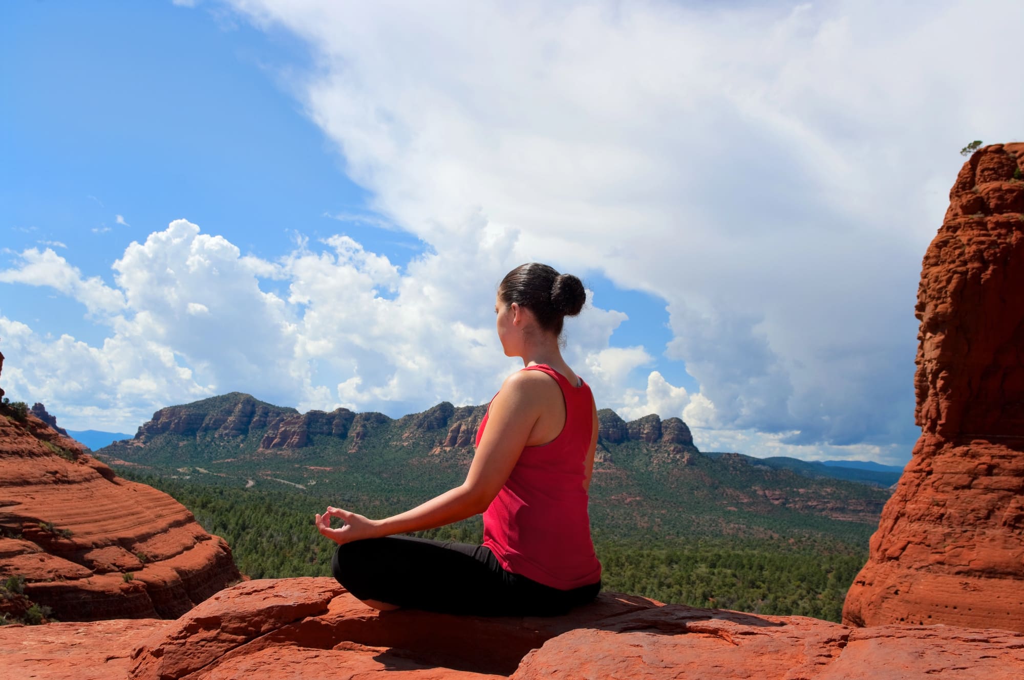 A woman sitting on top of a rock in the desert.